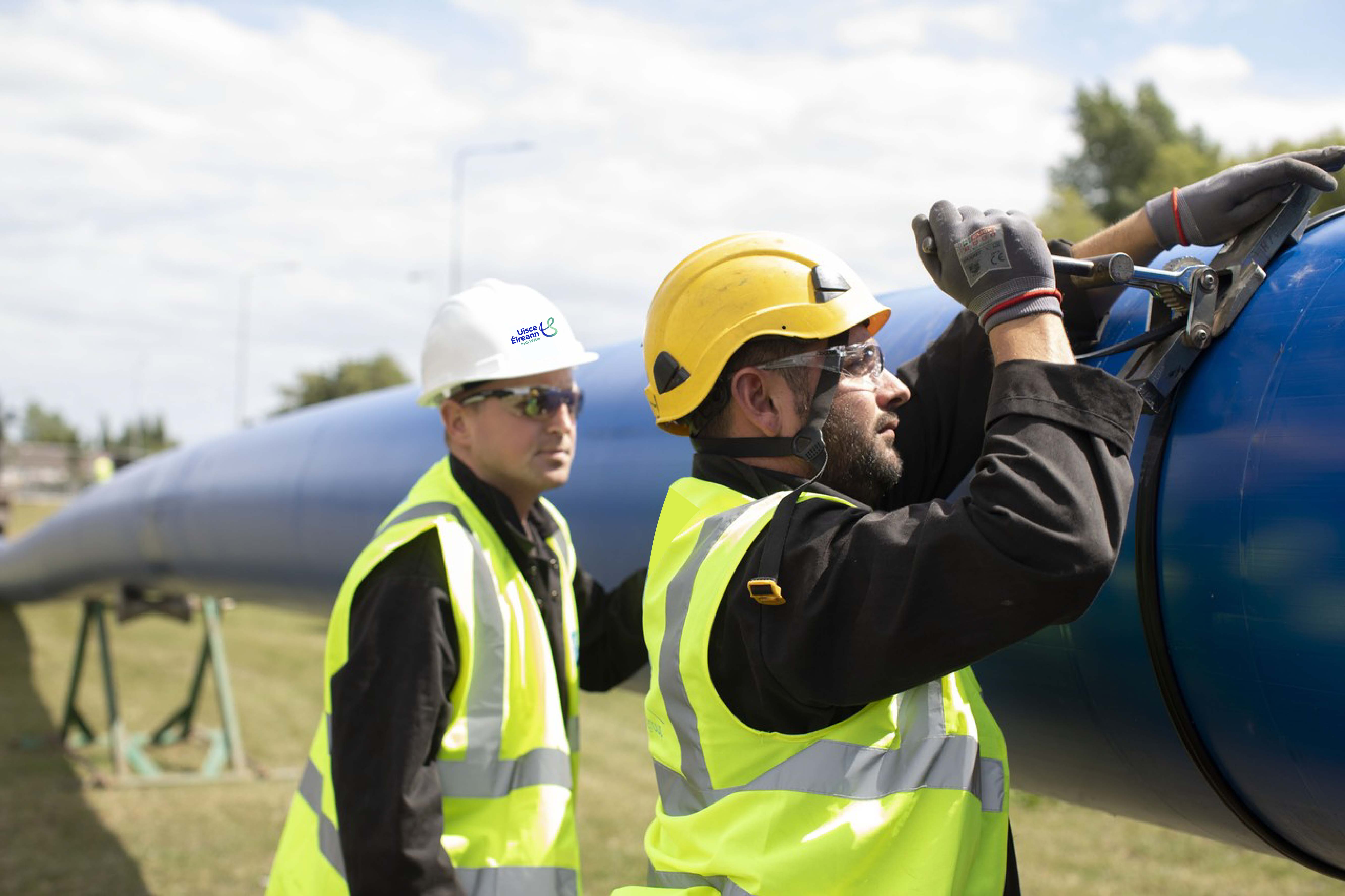 Two Uisce Éireann workers working on a large blue pipe