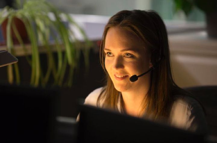 A woman with a microphone sitting at a computer