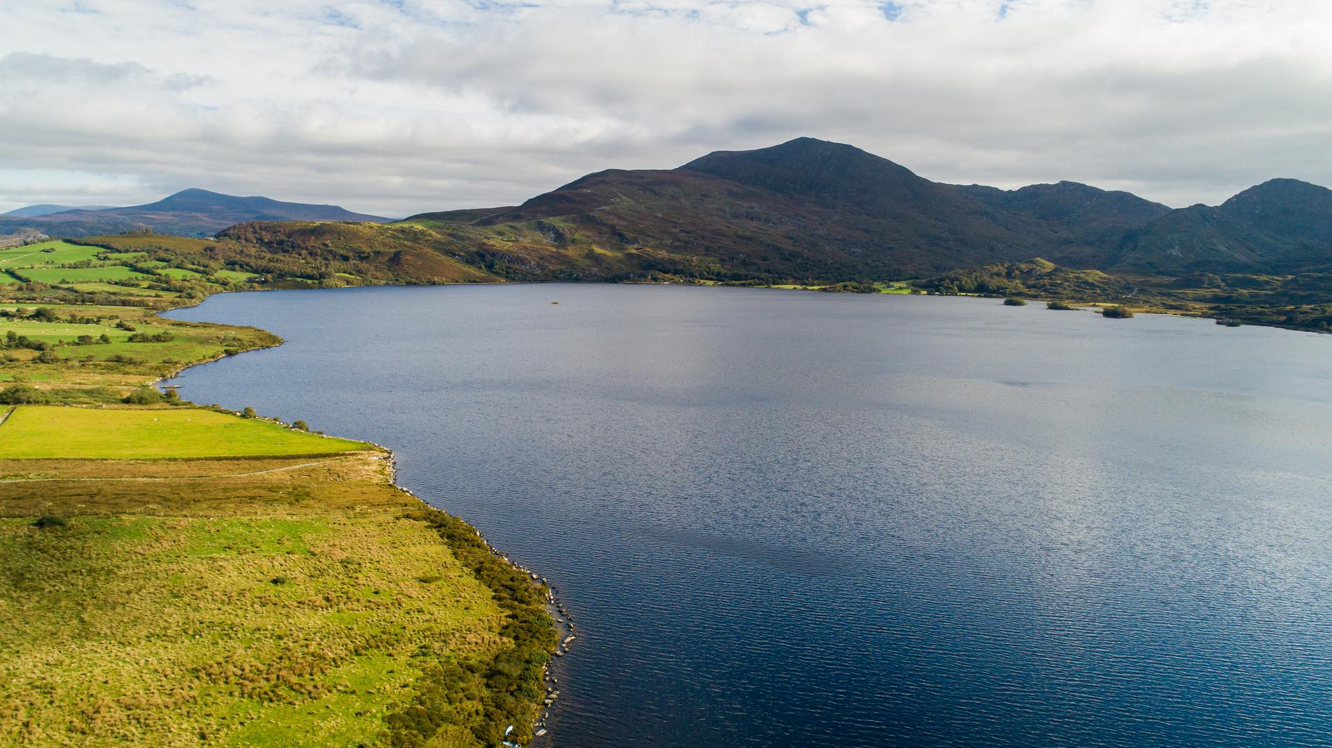 A large lake by some mountains and fields