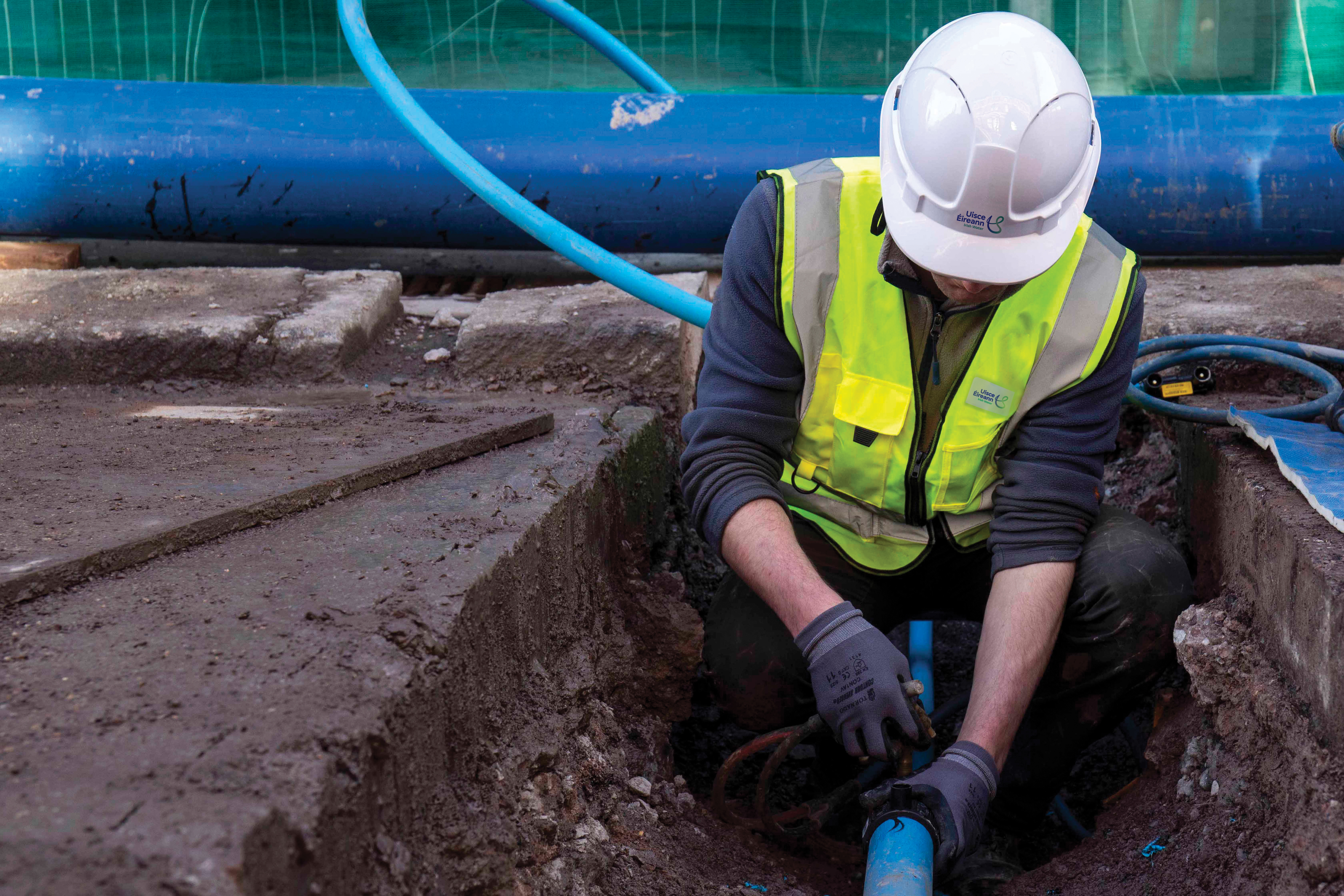 Uisce Éireann worker fixing a water pipe on a road