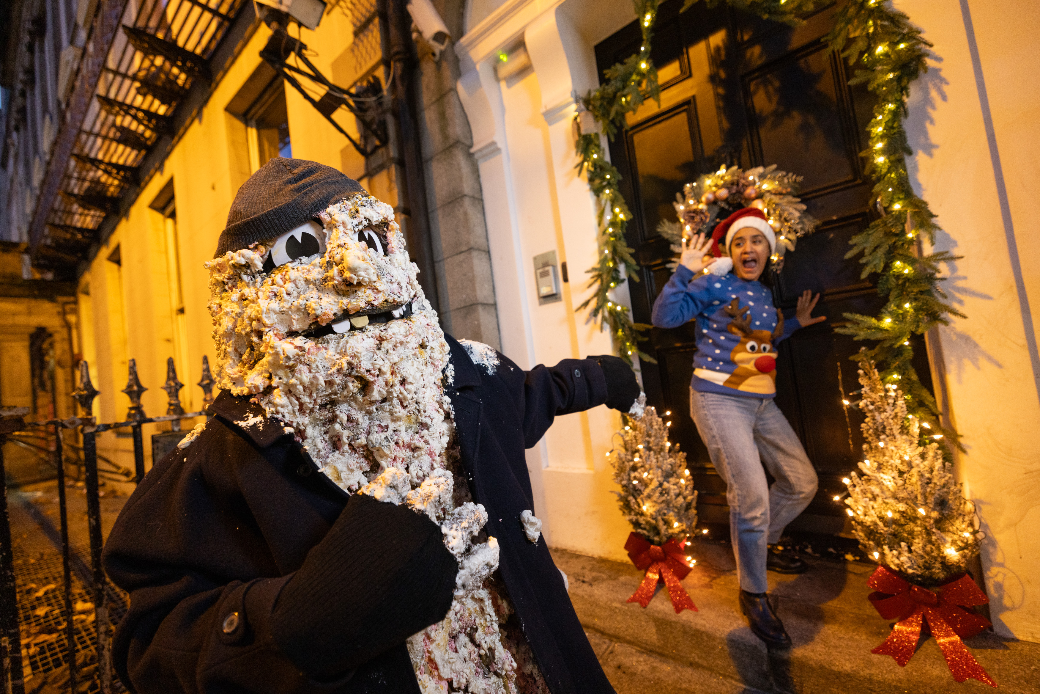 A scary mascot next to a woman in a Christmas hat screaming