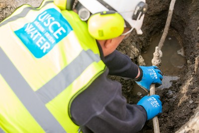 An Uisce Éireann worker fixing a small pipe in the ground