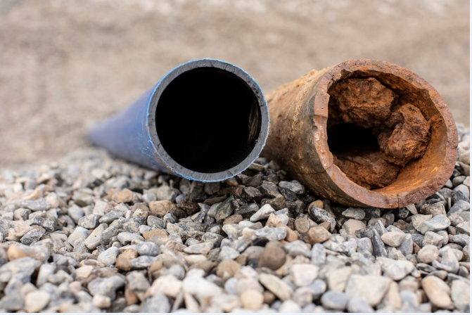 A new clean pipe next to an old damaged and rusty pipe