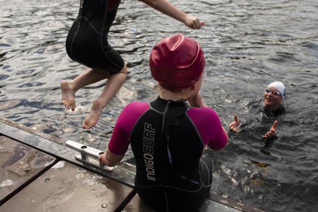 People swimming in the sea by a pier