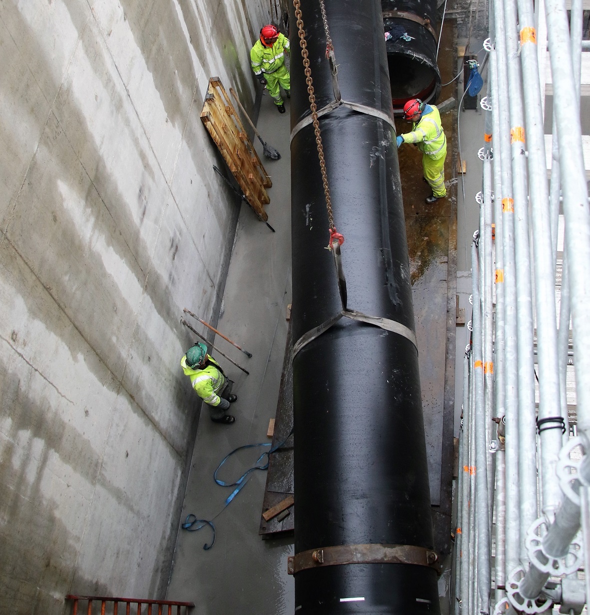 Workers placing a large pipe on the ground