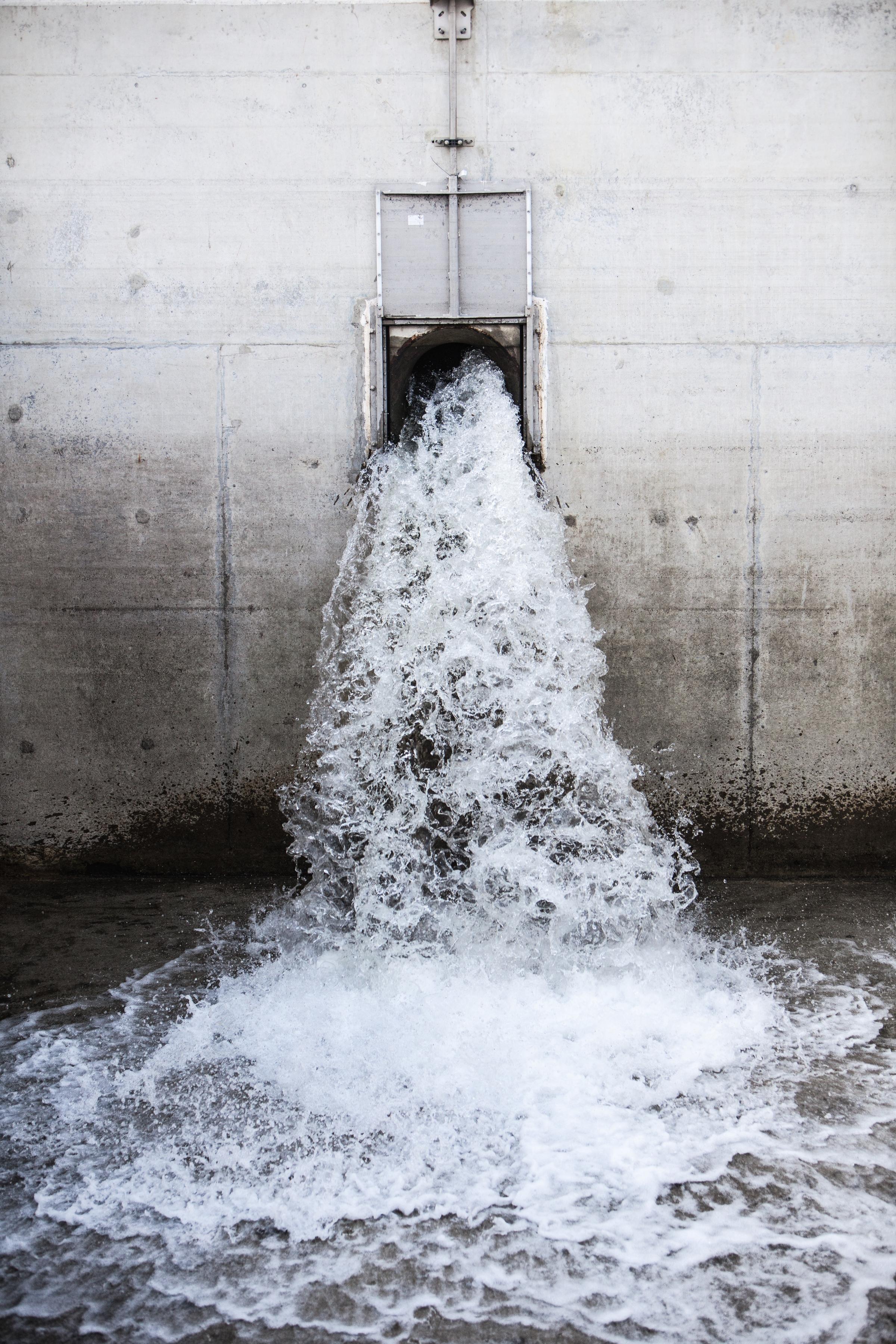 Water flowing out of a large pipe in a wall