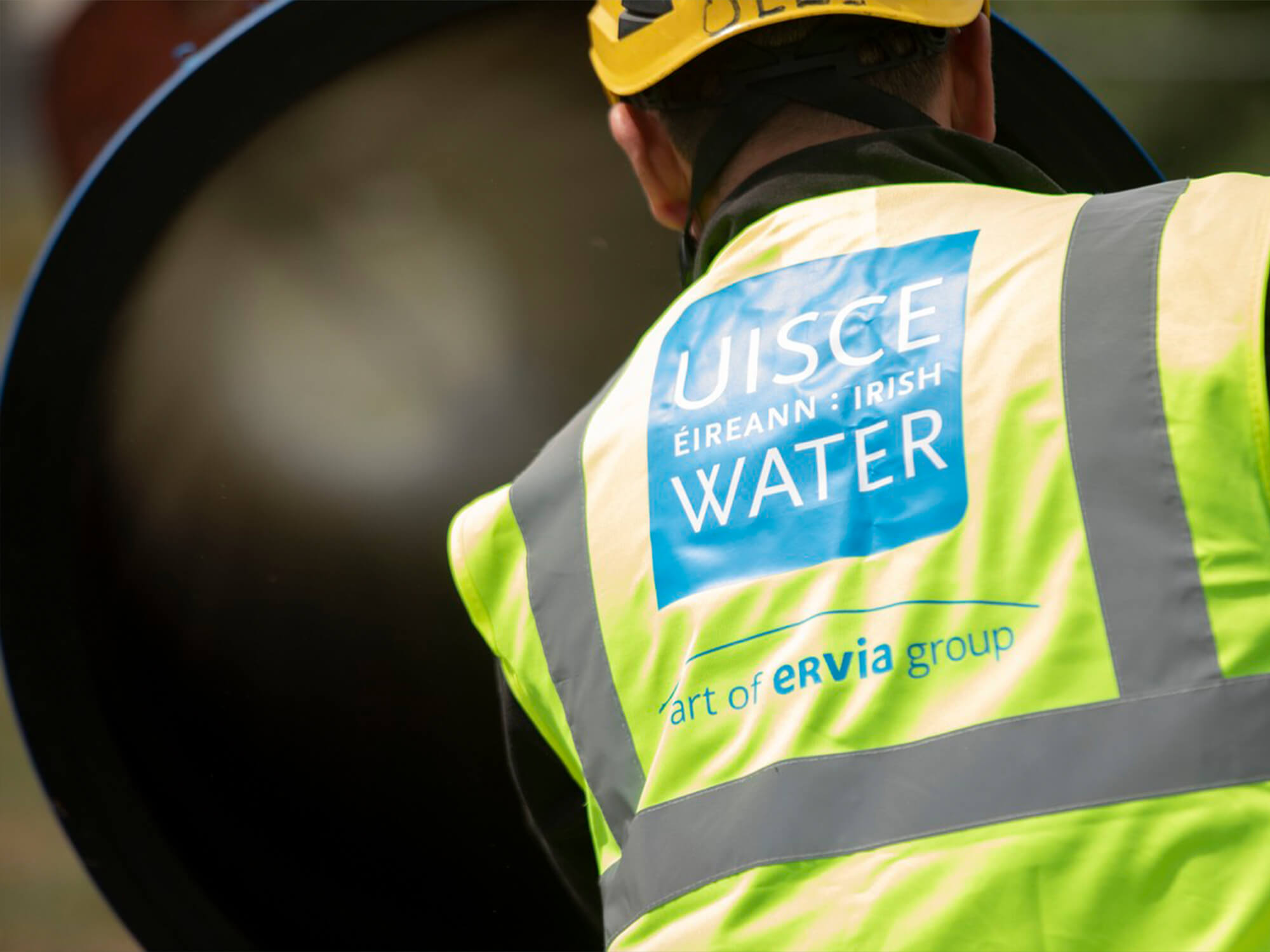 a Uisce Éireann worker looking at something in a opened lid cover 