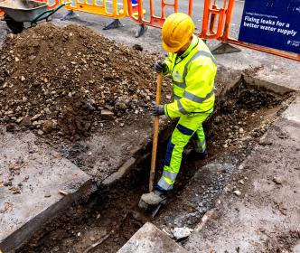 Worker in a trench working on pipes