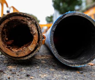 A new clean pipe next to an old damaged and rusty pipe