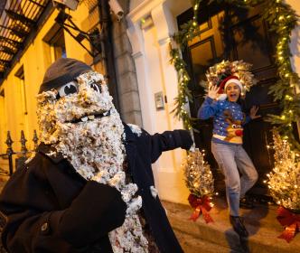 A scary mascot next to a woman in a Christmas hat screaming