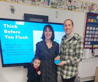 Two women and a young girl in front of a screen reading "Think before you flush'