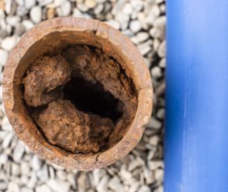 A new clean pipe next to an old damaged and rusty pipe